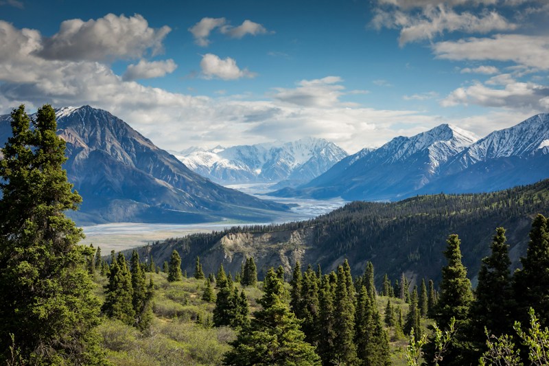 Snow-capped sunlit mountain peaks and daylight sky